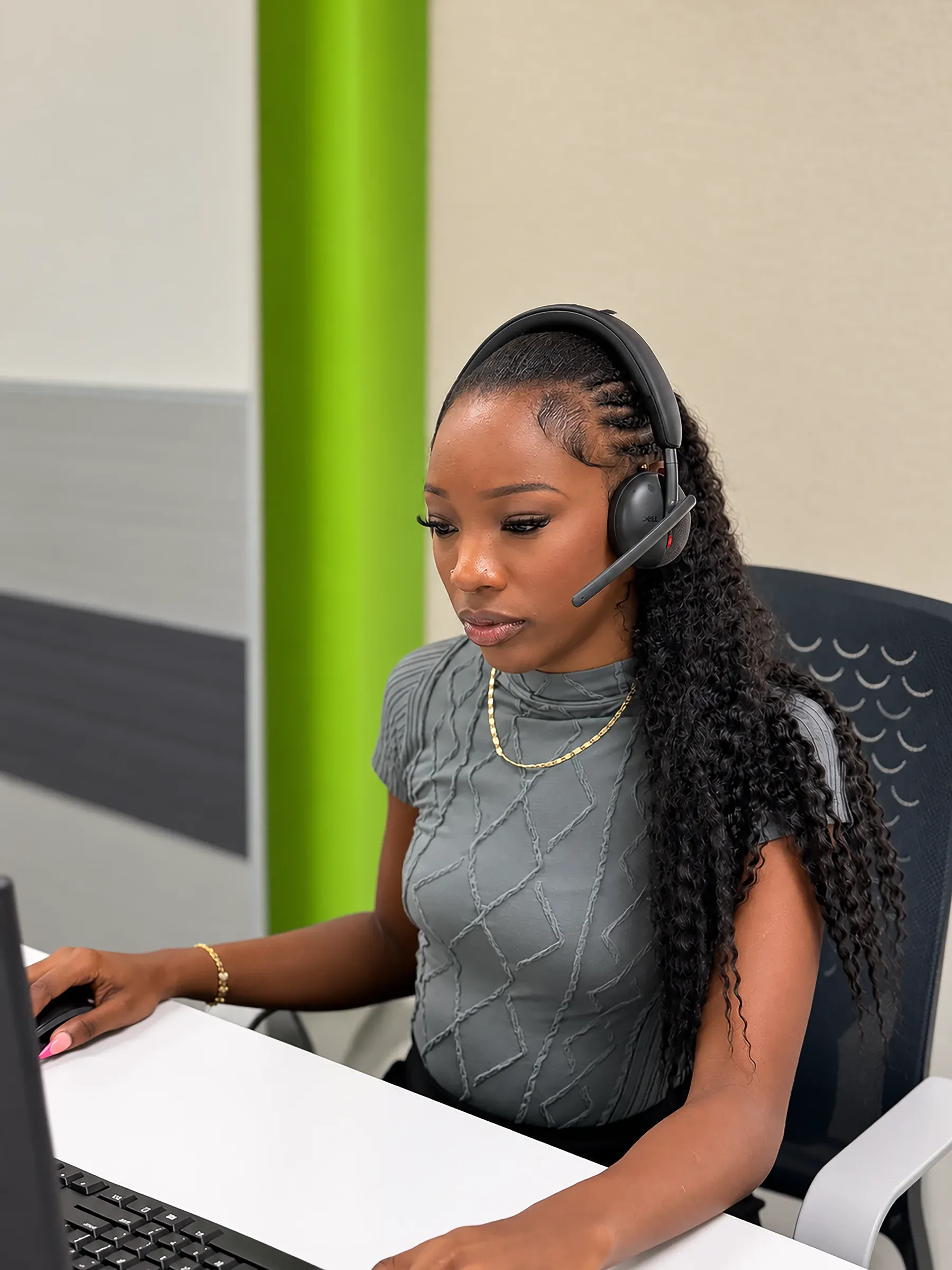 A CallServ agent wearing a headset at her workstation.