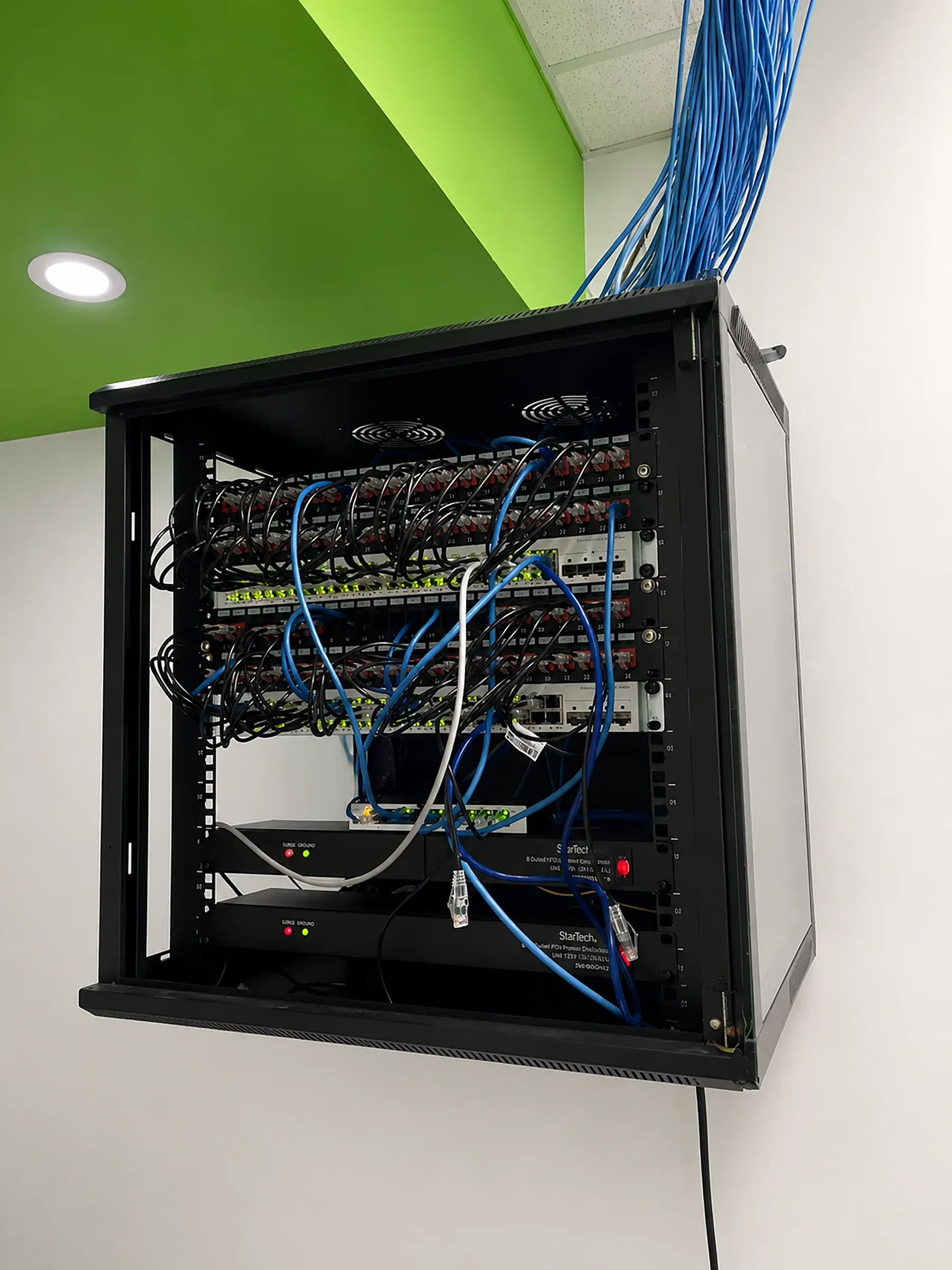 The wall mounted network cabinet in the CallServ building, with patch panels and structured cabling.