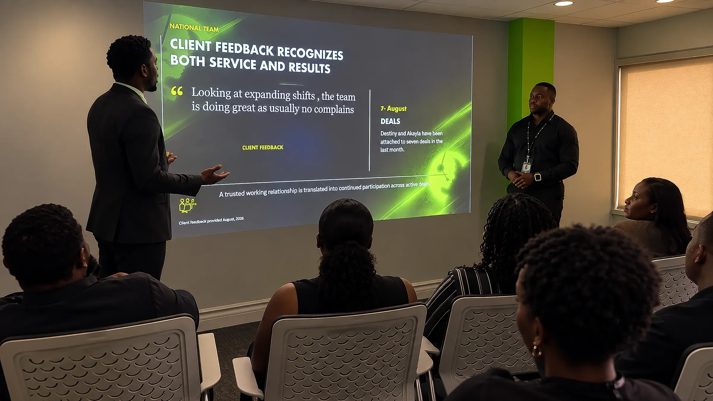 A CallServ manager presenting a client feedback summary to colleagues in a meeting room, with the slide projected behind him.